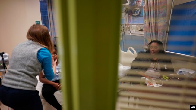 Brooklynn Chiles, 8, is examined during a followup visit at Children's National Hospital in Washington, Friday, Feb. 11, 2022, as her mother, Danielle watches.