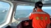 FILE - A Taiwanese coast guard member calls out on the megaphone for a Chinese coast guard ship at left to leave from the area around Kinmen County, Taiwan, July 11, 2024. Three crew members from a Chinese fishing boat were missing in the same area on Aug. 17, 2024.