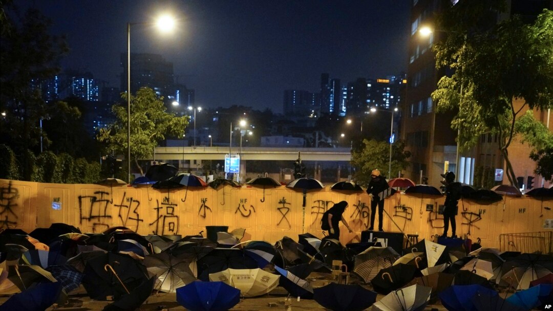Pro-democracy protesters barricade a road scattered with umbrellas and bricks outside the campus of the Hong Kong Baptist University in Hong Kong, Nov. 13, 2019. 