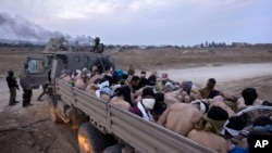 Soldados israelíes junto a un camión lleno de detenidos palestinos atados y con los ojos vendados, en Gaza, el viernes 8 de diciembre de 2023. 