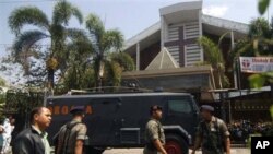 Indonesian police officer stands guard near an armored vehicle outside a church after an explosion in Solo, Central Java, Indonesia, Sunday, Sept. 25, 2011. A suicide bomber attacked the church packed with hundreds of worshippers Sunday, killing himself a