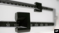 FILE - This April 3, 2018 file photo shows a closeup of a beam scale in New York. A government report released Dec. 20, 2018, shows that adult waistlines are expanding.