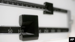 FILE - This April 3, 2018 file photo shows a closeup of a beam scale in New York. A government report released Dec. 20, 2018, shows that while adult waistlines have been expanding, the average height of U.S. men actually fell slightly over the past decade
