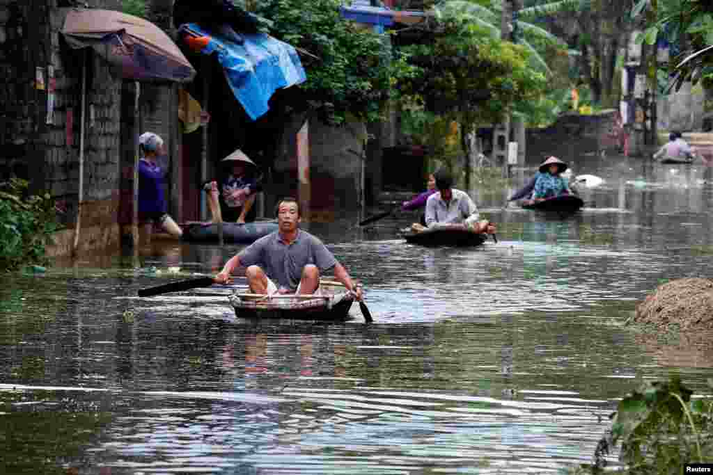 Residents paddle boats in a flooded village after heavy rain caused by a tropical depression in Hanoi, Vietnam.