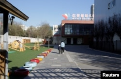 A child walks with a parent at the kindergarten run by pre-school operator RYB Education Inc being investigated by China's police, in Beijing, Nov, 24, 2017.