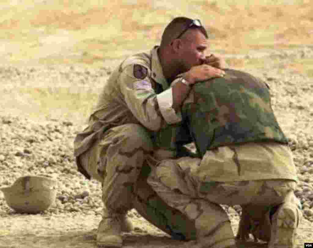 ABŞ hərbi zabiti Brian Pacholski eyni şəhərdə (Toledo, Ohio) boya başa çatdığı dostu və həmkarı David Borelli sakitləşdirir.&nbsp; Foto Bağdaddan 50 kilometr şimalda Bələd şəhərindəki hərbi bazanın girəcəyində çəkilib (13 iyun, 2003).&nbsp; Borell üç iraqlı uşağın partlayıcı quğudan yaralandığını gördükdən sonra tab gətirmədi.&nbsp; Foto: Toledoblade.com