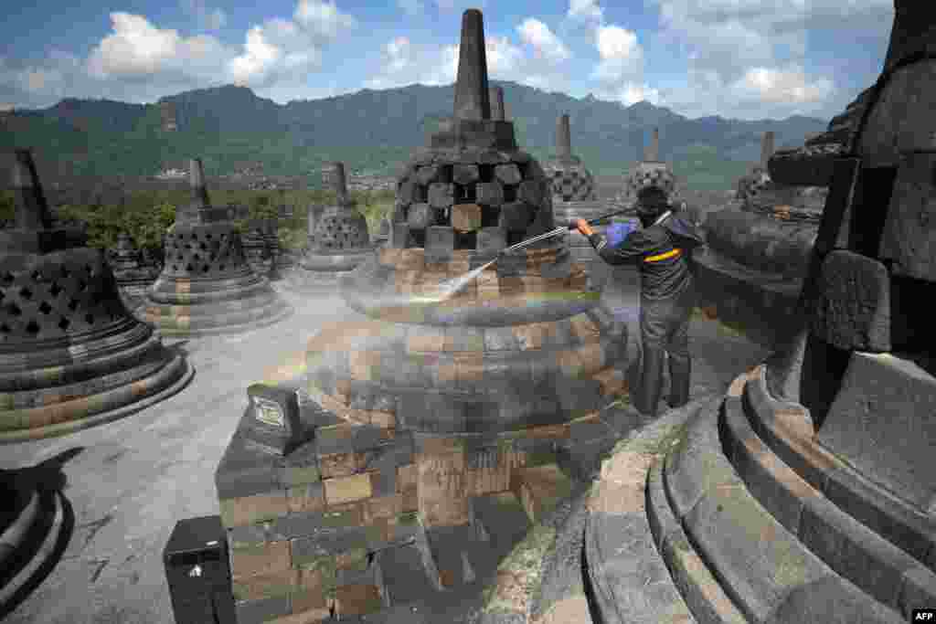 A worker cleans volcanic ash off the stupas at the Borobudur temple in Magelang Regency a day after Mount Merapi erupted in nearby Sleman, sending a plume of ash into the sky.
