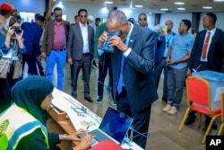 Somaliland President Muse Bihi Abdi, center, gets his biometrics registered before casting his vote inside a polling station during the presidential election in Hargeisa, Somaliland, Nov. 13, 2024.