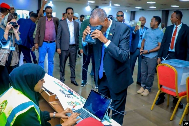 Somaliland President Muse Bihi Abdi, center, gets his biometrics registered before casting his vote inside a polling station during the presidential election in Hargeisa, Somaliland, Nov. 13, 2024.