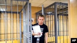 ARCHIVO. Iván Golunov, un destacado reportero investigador ruso, que trabajó para el portal independiente Meduza, sale de una jaula de metal en una corte de Moscú, en esta foto del 8 de junio de 2019.