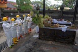 Sejumlah orang mengenakan alat pelindung diri (APD) mendoakan jenazah orang yang meninggal akibat Covid-19 di krematorium di Bangli, Bali, 10 Oktober 2020. (Foto: Antara via Reuters)