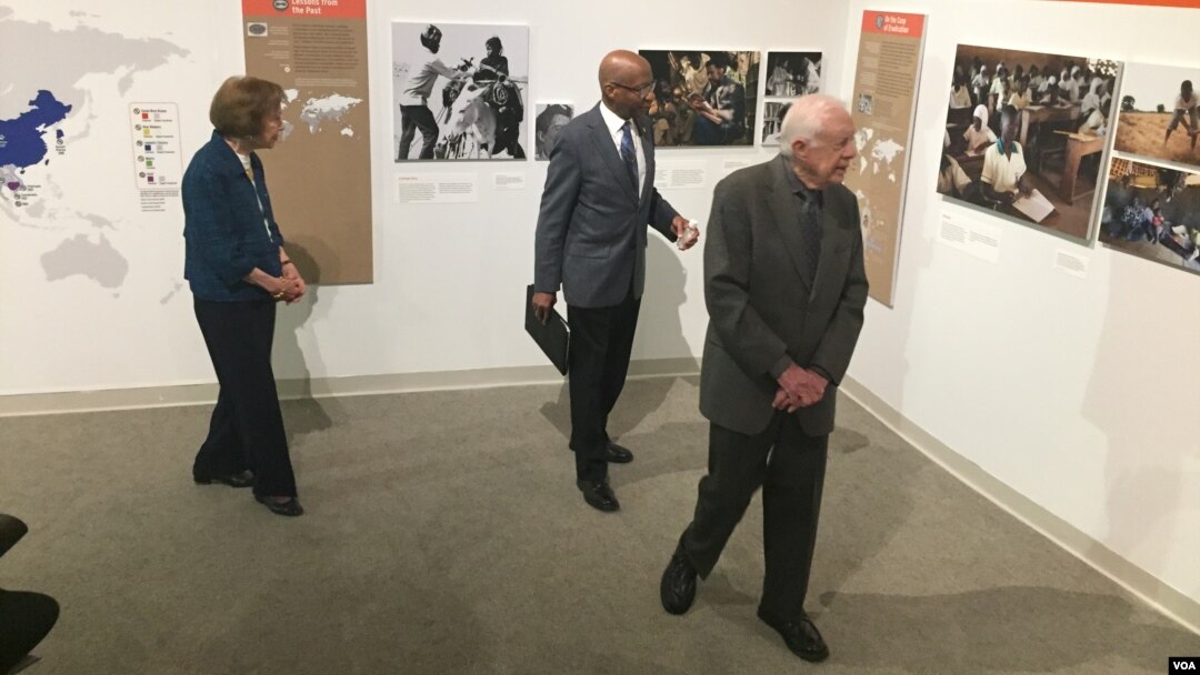 Former President Jimmy Carter and former first lady Rosalynn Carter tour the "Countdown to Zero" with Donald Hopkins, former director of Carter Center Health Programs, during a press event at the Jimmy Carter Library and Museum in Atlanta, Georgia, Jan. 11, 2017. (K. Farabaugh/VOA)