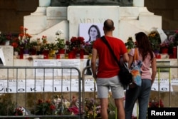 FILE - People visit a makeshift memorial to assassinated anti-corruption journalist Daphne Caruana Galizia, at the Great Siege Monument, in Valletta, Malta, April 22, 2018.