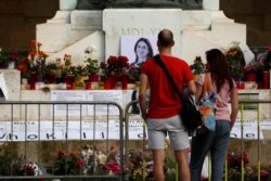 FILE - People look at the makeshift memorial to assassinated anti-corruption journalist Daphne Caruana Galizia on the Great Siege Monument after the police blocked off access to it, in Valletta, Malta, April 22, 2018.