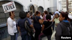 Una mujer de la tercera edad se identifica como la última de la fila para hacer compras en un supermercado del gobierno en Caracas.