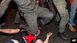 Seorang polisi Israel menindih seorang pedemo dalam unjuk rasa menentang Perdana Menteri Israel Benjamin Netanyahu di luar kantornya di Yerusalem, 22 Juli 2020. 
