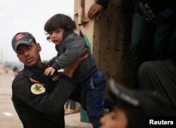 An Iraqi soldier helps a displaced child to get out of a truck as Iraqi forces battle with Islamic State militants, in western Mosul, March 28, 2017.