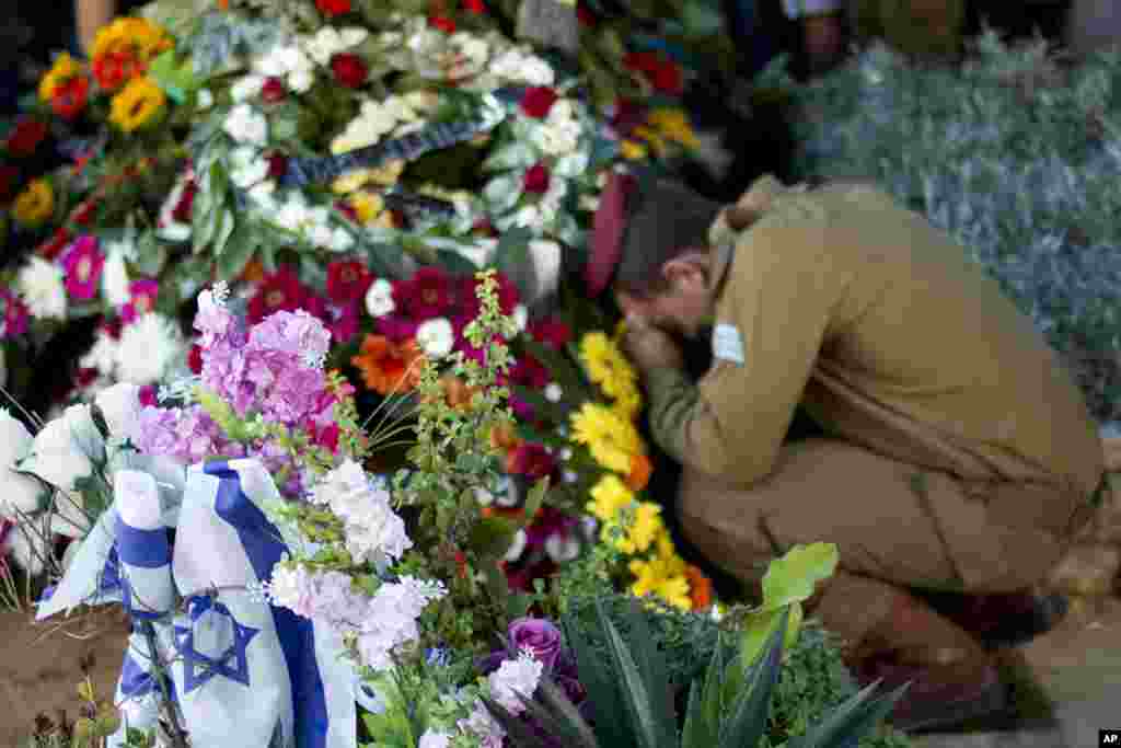 An Israeli soldier of the Maglan elite unit mourns over the grave of Staff Sgt. Matan Gotlib, a Maglan elite unit soldier, during his funeral in the military cemetery in Rishon Letzion, central Israel, July 31, 2014.
