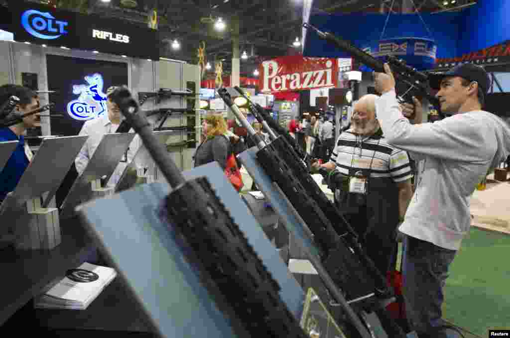 Scott Biegler (R), owner of Scotty's Guns in Timber Lake, South Dakota, looks over a Colt Marksman rifle during the annual SHOT (Shooting, Hunting, Outdoor Trade) Show in Las Vegas January 15, 2013. Gun dealers at the show are reporting booming sales resu