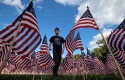 FILE - Jackson Tucker walks through the field of 3,000 U.S. flags placed in memory of the lives lost in the September 11, 2001 attacks, at a park in Winnetka, Illinois, Sept. 10, 2016.