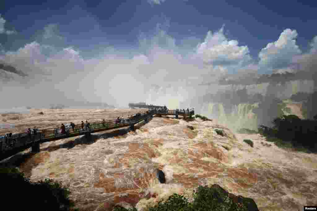 Tourists visit the Iguazu Falls walkway as it reopens to the public after being temporarily closed due to the high water flow from recent heavy rains, in Foz do Iguacu, Parana state Brazil, Dec. 11, 2024.