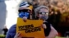 A Biden supporter holds a sign reading 'Voters decide' at a protest held by supporters of US President Donald Trump outside the Wisconsin State Capitol on Nov. 7, 2020.