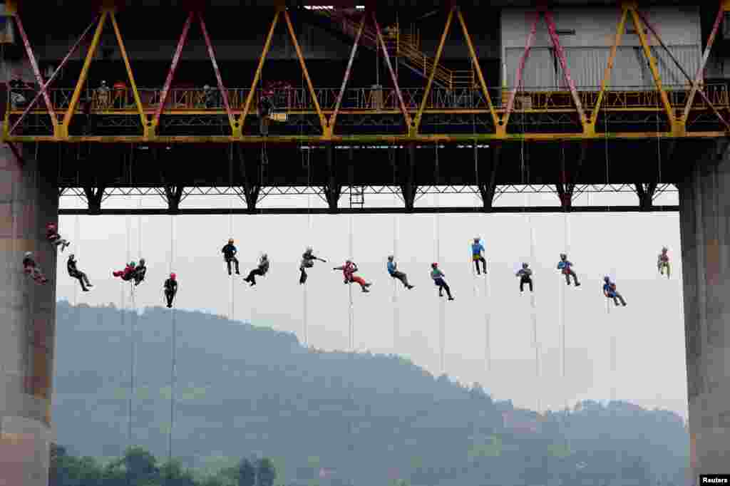 Warga bergelantungan dengan tali di sebuah jembatan di Chongqing, China pada saat latihan operasi penyelamatan.