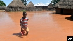 A boy stands outside his family home, which has been submerged by floods following prolonged heavy rains in Tana Delta, Coastal Kenya, April 27, 2018. 