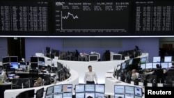 Traders at their desks in front of the DAX board at the Frankfurt stock exchange, August 14, 2012. 