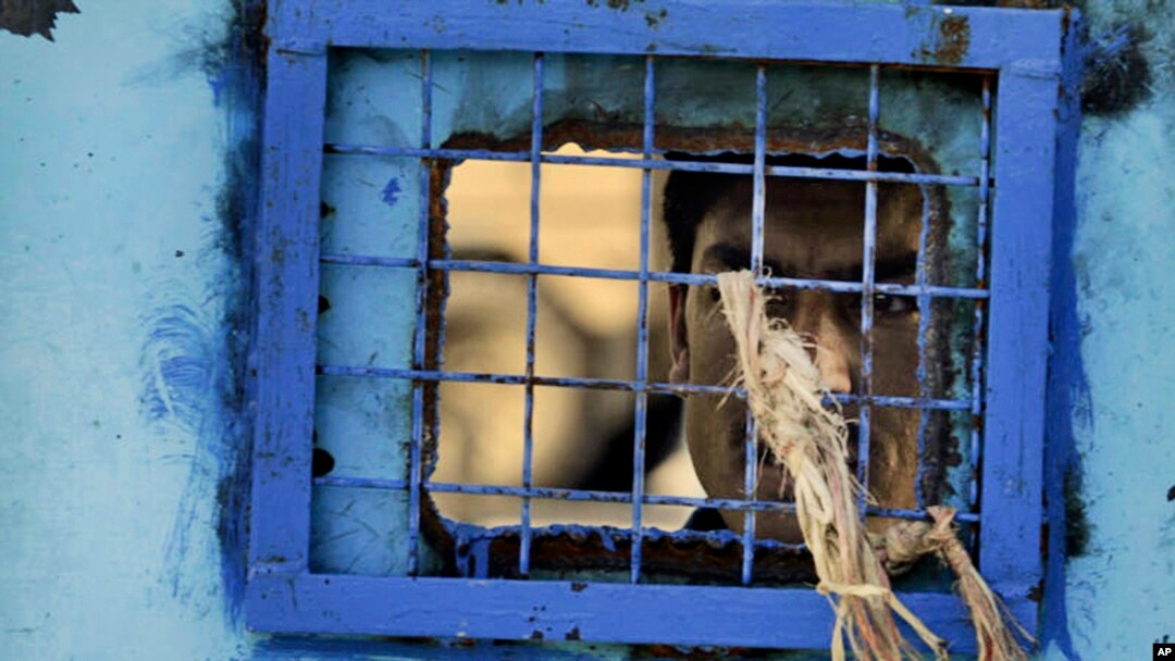 FILE - A prisoner looks out of his cell window at the main prison in Kandahar, Afghanistan.