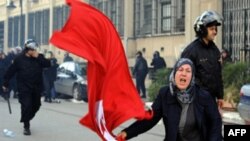 A Tunisian woman waves the national flag in front of the interior ministry during clashes between demonstrators and security forces in Tunis, 14 Jan 2011.