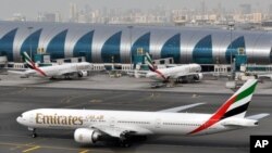 FILE- In this Wednesday, March 22, 2017 file photo, an Emirates plane taxis to a gate at Dubai International Airport at Dubai International Airport in Dubai, United Arab Emirates. The Middle East's biggest airline says it is reducing flights to the United States because of a drop in demand caused by tougher U.S. security measures and attempts by the Trump administration to ban travelers from a number of Muslim-majority nations. (AP Photo/Adam Schreck, File) c