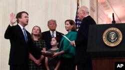 Retired Justice Anthony Kennedy, right, ceremonially swears-in Supreme Court Justice Brett Kavanaugh, as President Donald Trump looks on, in the East Room of the White House in Washington, Monday, Oct. 8, 2018. Ashley Kavanaugh holds the Bible and daughters Margaret, left, and Liza, look on. (AP Photo/Susan Walsh)