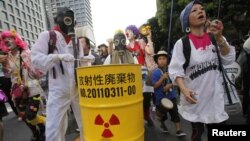 Para demonstran anti PLTN mengenakan masker melakukan unjuk rasa di depan kantor pusat perusahaan listrik Jepang, TEPCO, di Tokyo Minggu (29/7). Demonstran menentang doperasikannya kembali dua PLTN di Jepang. 