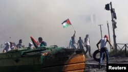 Warga Palestina melempar batu dalam pertempuran dengan polisi Israel di Shuafat, sebuah pinggiran kota Arab di Yerusalem (3/7). 