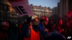 Striking workers are lit by a flare during a demonstration, Thursday, Jan. 16, 2020 in Paris.