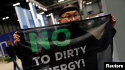 An activist protests as part of the Make Big Polluters Pay campaign inside the venue of the U.N. climate change conference (COP25) in Madrid, Dec, 4, 2019.
