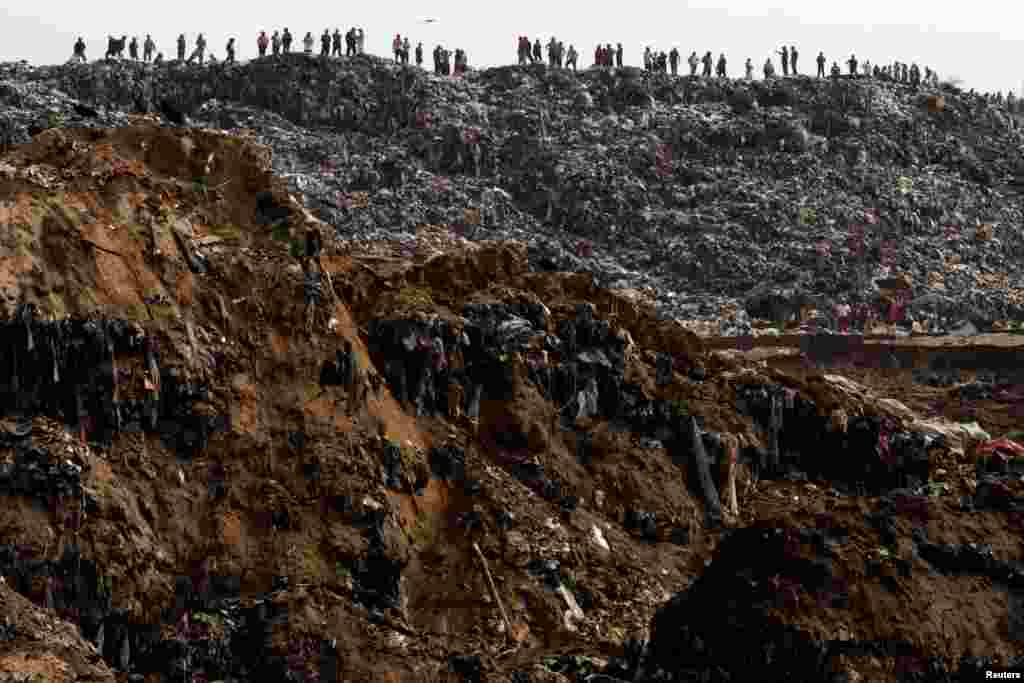 Garbage collectors look at rescue teams (not pictured) working at the site where a massive pile of garbage collapsed at a landfill dumpsite in Guatemala City, Guatemala, April 27, 2016.