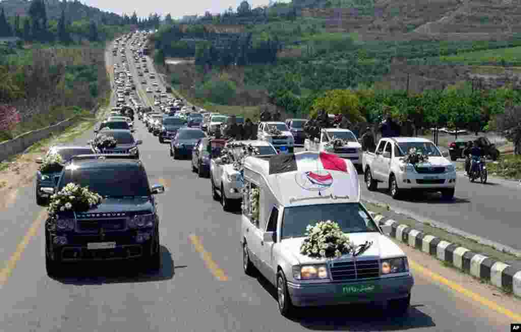 Sebuah konvoi membawa peti mati komandan Pasukan Pertahanan Nasional pro-pemerintah, Hilal Assad, dalam pemakamannya di propinsi Latakia, 24 Maret 2014.