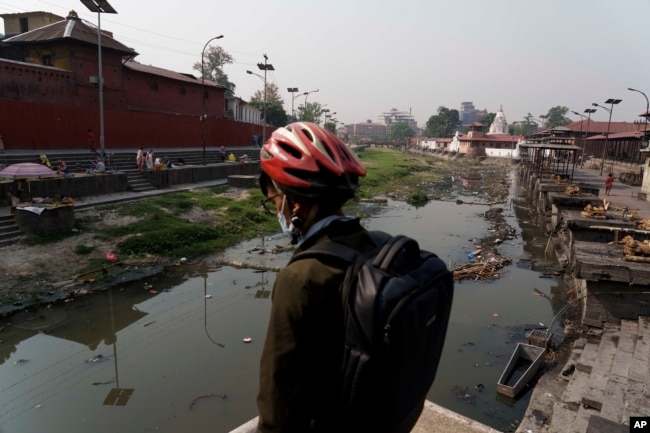 A man looks at the polluted Bagmati River from the Pashupatinath Temple in Kathmandu, Nepal, Monday, April 25, 2022. The Bagmati’s sludge oozes past the temple, declared a World Heritage Site by UNESCO in 1979, and several other sacred sites in the city. (AP Photo/Niranjan Shrestha)