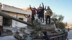 Pendukung oposisi Suriah berdiri di atas tank tentara Suriah yang direbut di Kota Maarat al-Numan, barat daya Aleppo, Suriah, 30 November 2024. (Foto: AP)