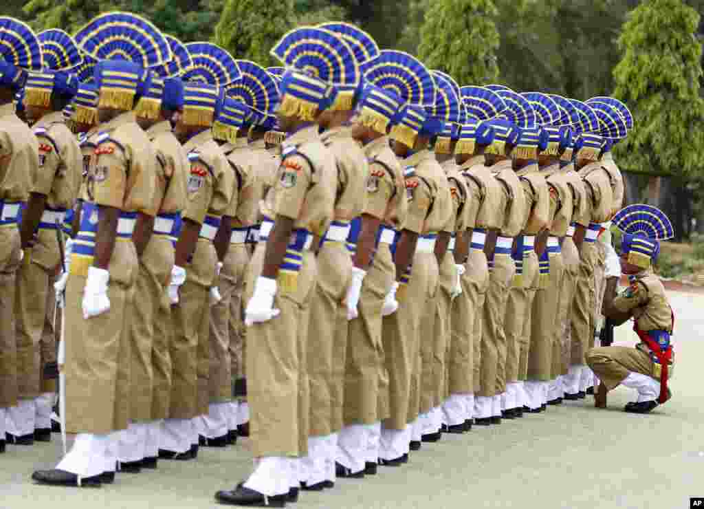 Seorang anggota polisi paramiliter India beristirahat di belakang rekan-rekannya saat upacara di Bangalore, India.