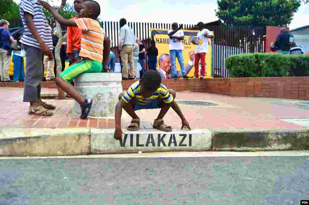 A young boy traces the letters on the Vilakasi Street sign outside of Nelson Mandela&#39;s home in Soweto, now the Nelson Mandela National Museum, Dec. 12, 2013. (Peter Cox for VOA) 