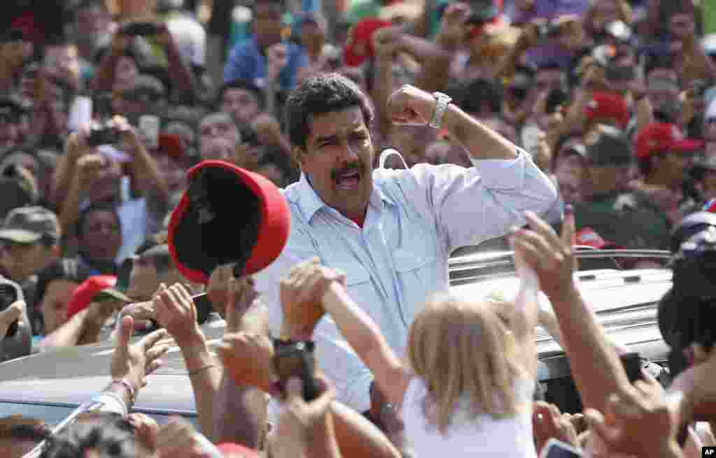 Venezuela&#39;s interim president Nicolas Maduro gestures to supporters as he leaves a polling station in Caracas, April 14, 2013. 