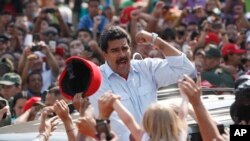 Kaimu rais wa Venezuela Nicolas Maduro akiwapungia mkono wafuasi wake baada ya kupiga kura mjini Caracas, Venezuela, Jumapili, Apr. 14, 2013. 