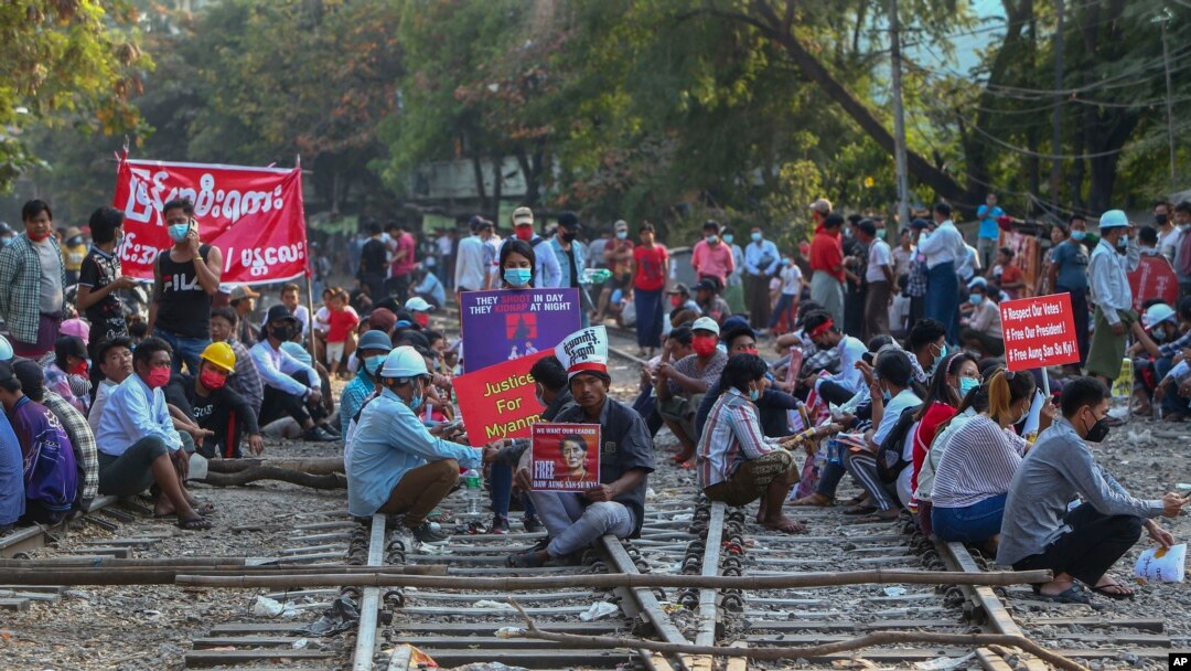 Para demonstran berunjuk rasa dengan membawa plakat dan duduk di rel kereta api untuk memblokir layanan kereta api, dalam aksi protes terhadap kudeta militer di Mandalay, Myanmar, 17 Februari 2021. (AP Photo/File)