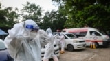 This photo taken on October 1, 2020 shows a volunteering adjust his personal protective equipment (PPE) next to ambulances as they prepare gather people suspected of having the COVID-19 novel coronavirus to be transferred to a quarantine centre in Yangon.