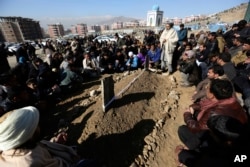 Villagers pray in front of the grave of a victim of Tuesday's two bombings in Kabul, Afghanistan, Jan. 11, 2017.