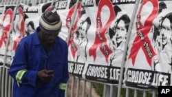 A man uses his mobile phone while passing World AIDS Day banners in Sandton, Johannesburg, South Africa, Dec. 1, 2014.