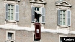 Pope Francis is seen in the window of the Apostolic Palace in Saint Peter's Square at the Vatican, Jan. 1, 2014.